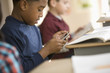 Mixed race boy text messaging on cell phone in school