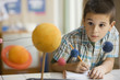 Mixed race boy studying the planet model in classroom