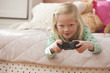 Caucasian girl laying on bed playing video game