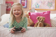 Caucasian girl laying on bed playing video game