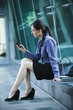 Caucasian businesswoman sitting outdoors using cell phone