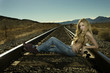 Caucasian woman laying on railroad tracks