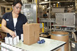 Hispanic worker packing boxes in factory