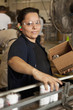 Hispanic worker packing boxes on assembly line