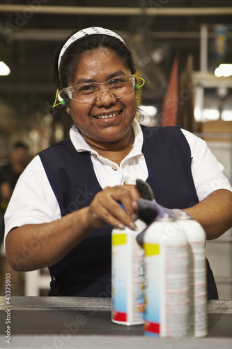 Photo: Hispanic woman with cans in factory Hispanic woman with cans in factory