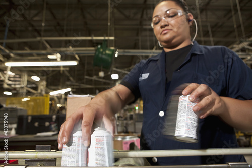 Photo: Hispanic worker picking up cans from assembly line Hispanic worker picking up cans from assembly line
