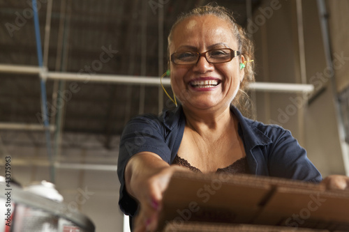 Photo: Hispanic woman packing boxes in factory Hispanic woman packing boxes in factory