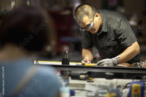 Photo: Asian man working in electronics factory Asian man working in electronics factory
