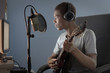 Mixed race boy strumming guitar and recording it on computer
