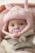 Caucasian baby girl in rabbit hat sucking pacifier
