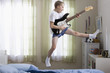 Caucasian boy jumping and playing guitar