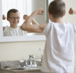 Caucasian boy flexing muscles in bathroom
