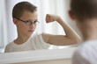 Caucasian boy flexing muscles in bathroom