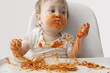 Mixed race baby boy eating spaghetti