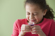 Hispanic girl taking cough syrup