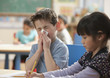 Caucasian boy blowing nose in classroom