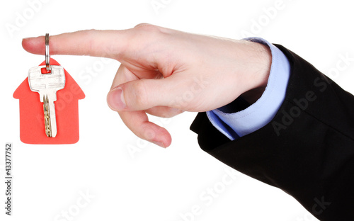 Photo: Key with house-shaped charm in hand isolated on white Key with house-shaped charm in hand isolated on white