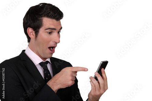 Photo: Surprised man pointing to his mobile phone Surprised man pointing to his mobile phone