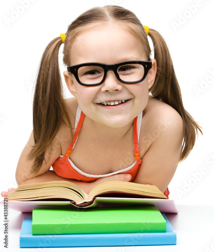 Photo: Cute cheerful little girl reading book Cute cheerful little girl reading book