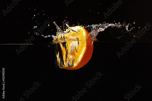 Photo: Halved fresh orange falling into the water with a splash Halved fresh orange falling into the water with a splash