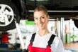 Auto Mechanikerin arbeitet an Auto auf Hebebühne