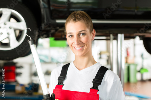 Photo: Auto Mechanikerin arbeitet an Auto auf Hebebühne Auto Mechanikerin arbeitet an Auto auf Hebebühne