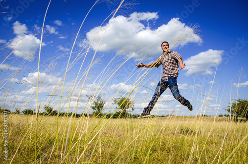 Photo: Young man jumping on dry meadow Young man jumping on dry meadow