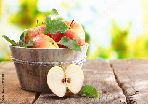 Photo: Wooden tub full and a halved fresh apple Wooden tub full and a halved fresh apple