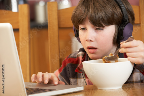 Photo: Boy Using Laptop Whilst Eating Breakfast Boy Using Laptop Whilst Eating Breakfast