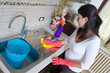 beautiful young housewife cleaning the furniture in the kitchen