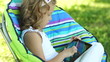 Girl with a tablet pc sitting in a chair. Thumbs up. Ok.