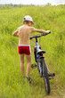 The boy and his bike on the grass of the field