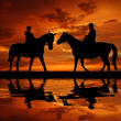 Silhouette cowboys with horses in the sunset