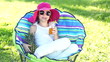 Happy girl drinking fruit juice and siting in a chair outdoors
