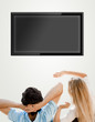 Young couple watching tv. Photo from behind. Lots of copyspace