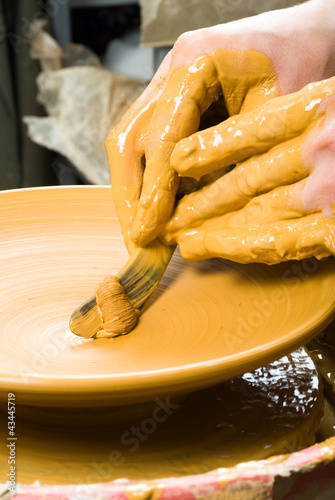Photo: hands of a potter, creating an earthen jar on the circle hands of a potter, creating an earthen jar on the circle