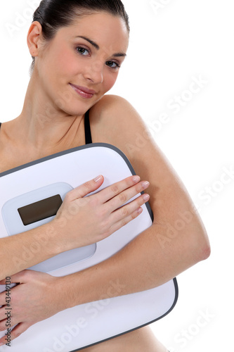 Foto: Woman holding bathroom scales Woman holding bathroom scales