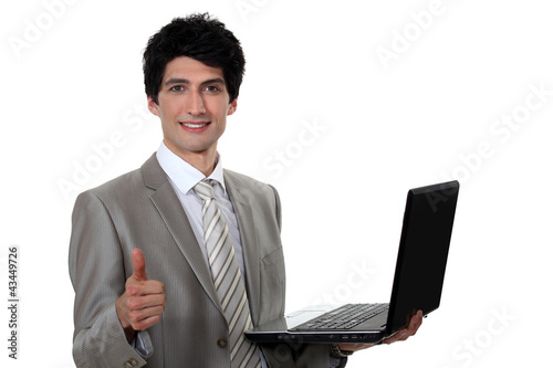 Foto: businessman holding a laptop and making a thumbs up sign businessman holding a laptop and making a thumbs up sign