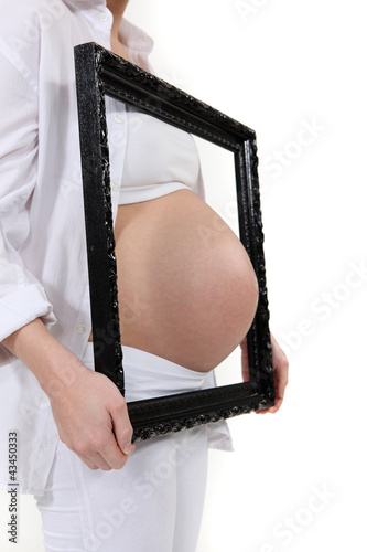 Photo: Pregnant woman poking belly through picture frame Pregnant woman poking belly through picture frame