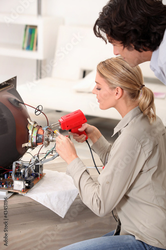 Foto: Woman fixing a television Woman fixing a television