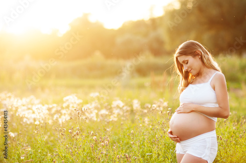 Photo: Beautiful pregnant woman relaxing in the park Beautiful pregnant woman relaxing in the park