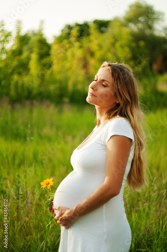 Photo: Beautiful pregnant woman relaxing in the park Beautiful pregnant woman relaxing in the park