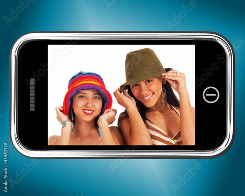 Photo: Two Teenage Girls In Hats Picture On Smartphone Two Teenage Girls In Hats Picture On Smartphone