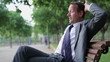 Video: Happy businessman relaxing on bench in the park, tracking shot Happy businessman relaxing on bench in the park, tracking shot
