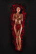 Beautiful woman against petals of red roses on black