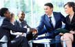 Two business man shaking hands with his team in office