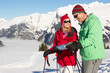 Couple Looking At Map Whilst On Ski Holiday In Mountains
