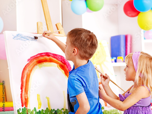 Foto: Child painting at easel. Child painting at easel.