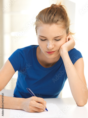 Photo: pensive teenage girl with pen and paper pensive teenage girl with pen and paper