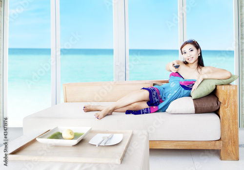 Photo: Asian woman watching tv by the beach Asian woman watching tv by the beach